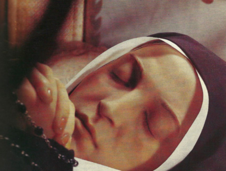 A close-up photograph of the serene, if waxy, face of the exhumed body of Saint Bernadette at the Convent of St. Gildard, Nevers, France.