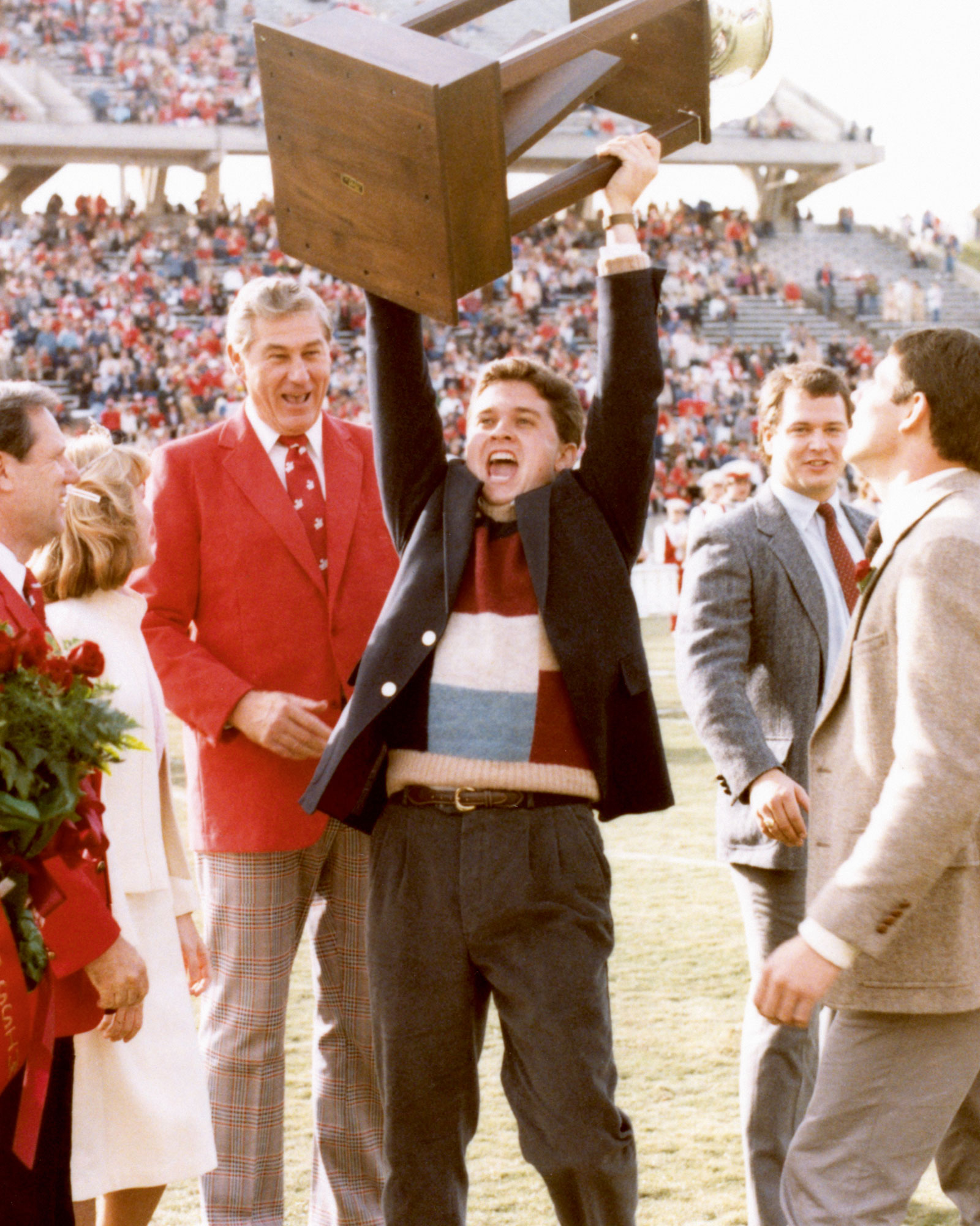 A photograph of a member of the Farmhouse fraternity hoisting the Interfraternity Council Caldwell Cup at North Carolina State University, September nineteen eighty-four.