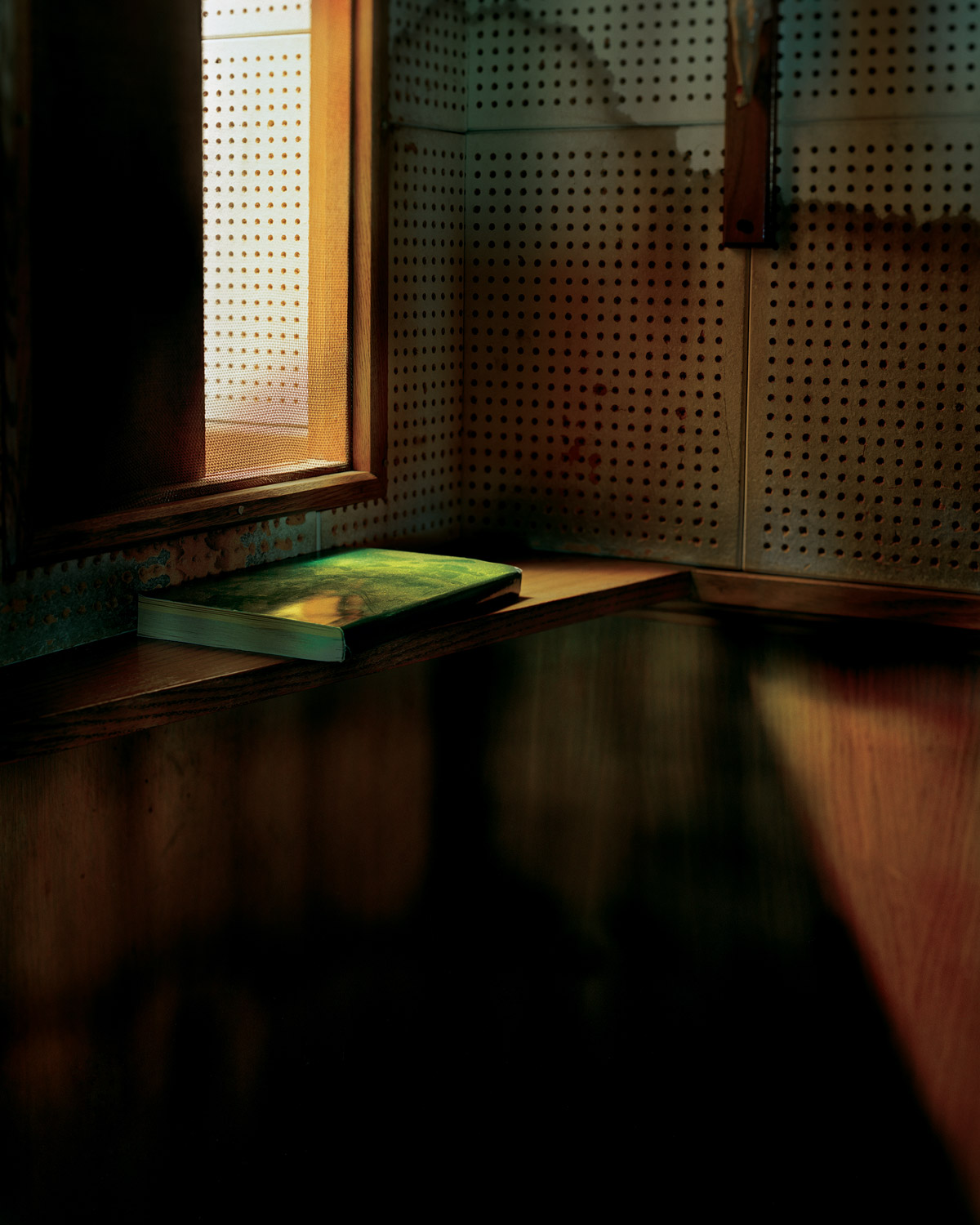 A photograph of the inside of a confessional booth, with water-stained light wood, which the artist associates with Saint Christopher.
