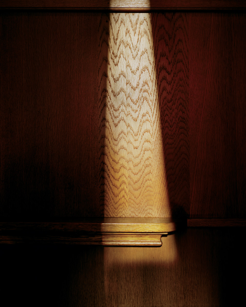 A photograph of the inside of a confessional booth, a streak of light illuminating the dark, which the artist associates with Saint Thomas More.