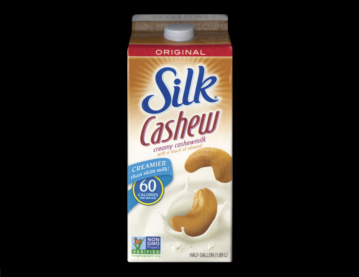 An image of Silk original creamy cashew milk featuring two cashew nuts, one above the other, in a splash.