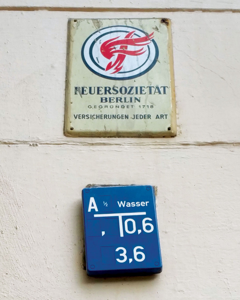 A photograph of two plaque markings on a building's wall, designating the building's fire insurance protection by Feuersozietät Berlin.