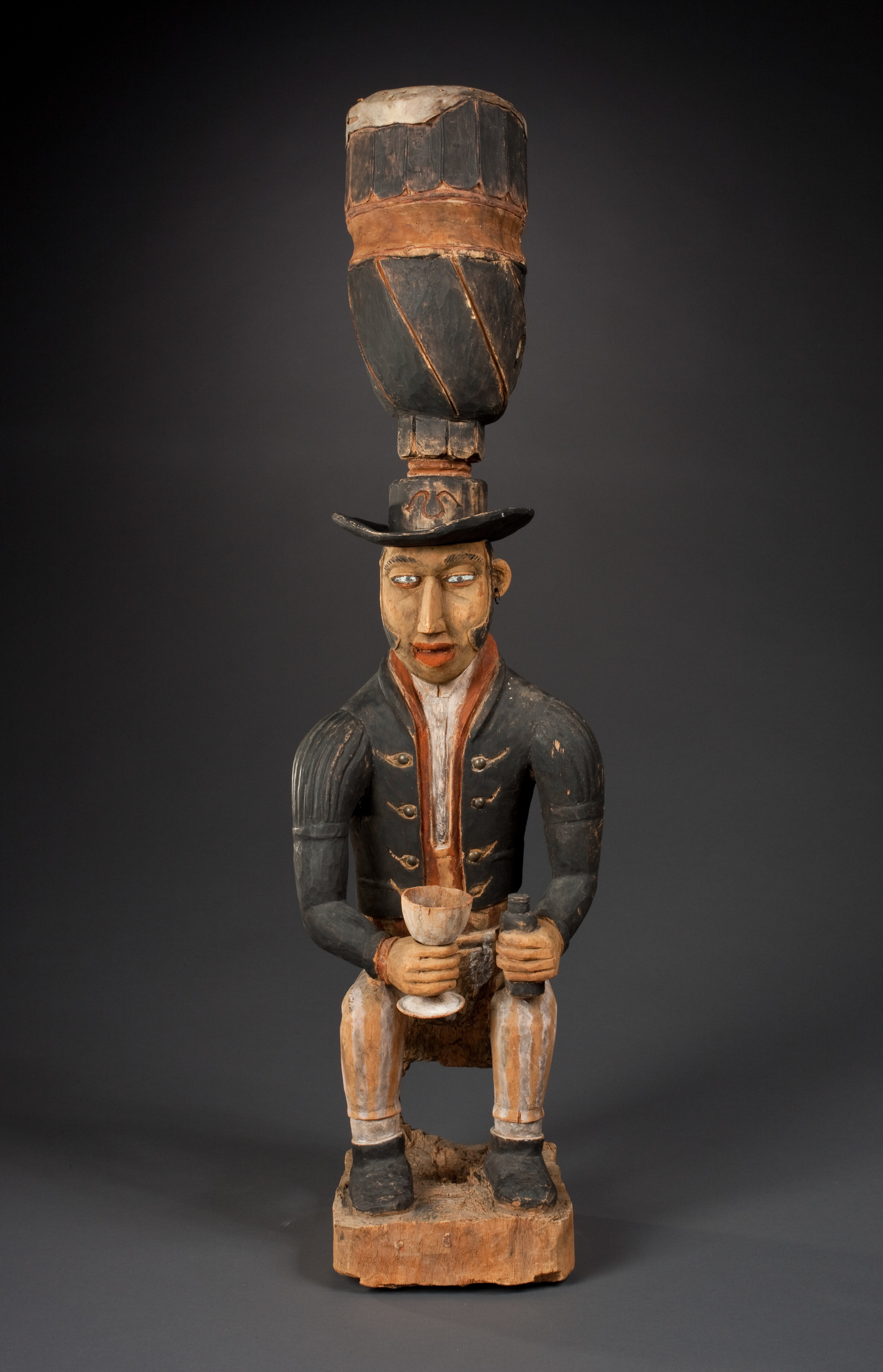 Early nineteenth-century Vili drum from the Loango Kingdom depicting a drunken European pouring himself whiskey.