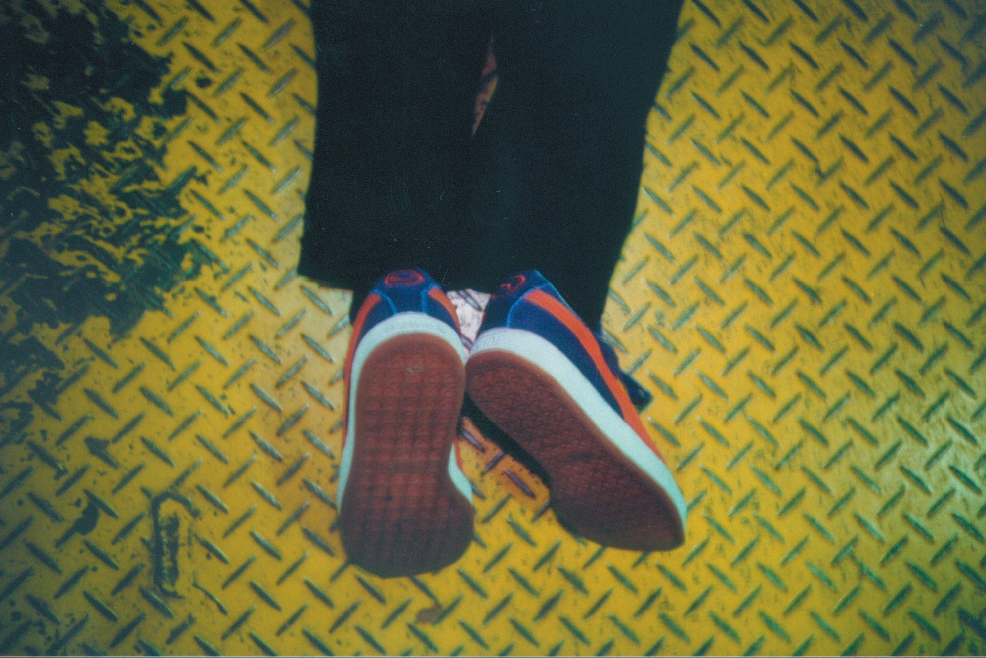 A Lomographic image depicting the feet of a person wearing sneakers.