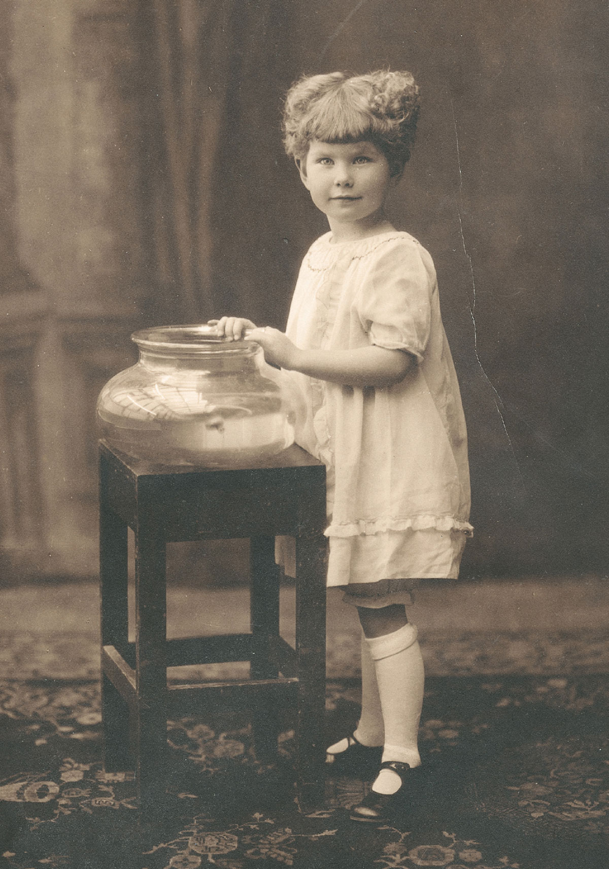 A photograph of a young girl in a dress and knee socks, taken before 1923.
