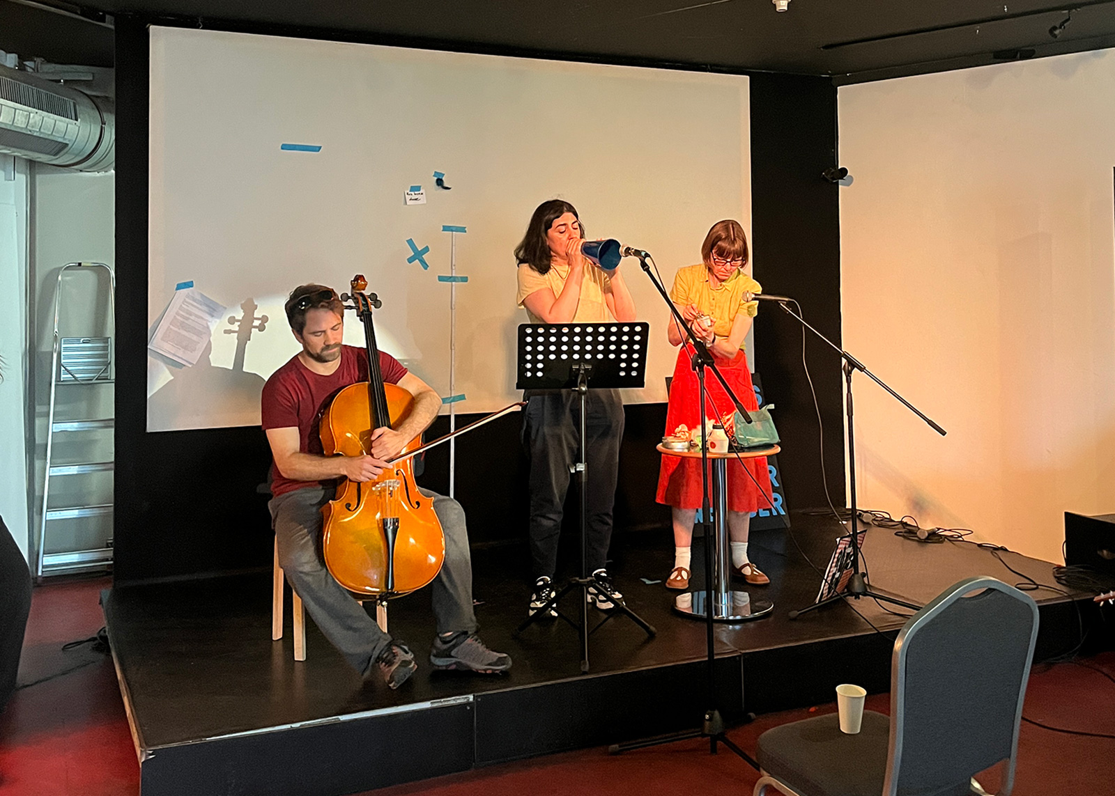 A photograph of three performers devising a radio program during rehearsals.