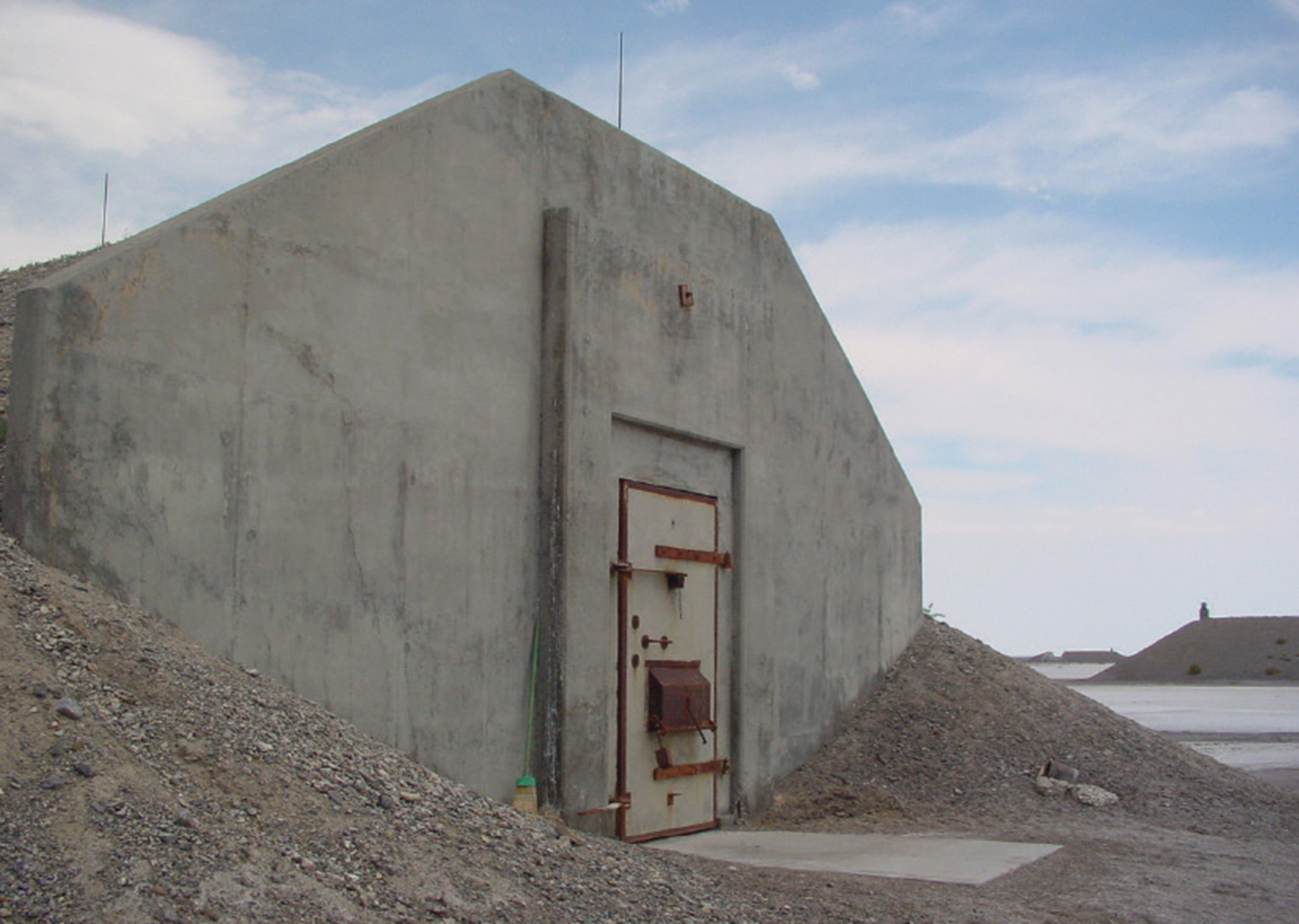 A photograph of a cement storage igloo with a rusting, barred door.