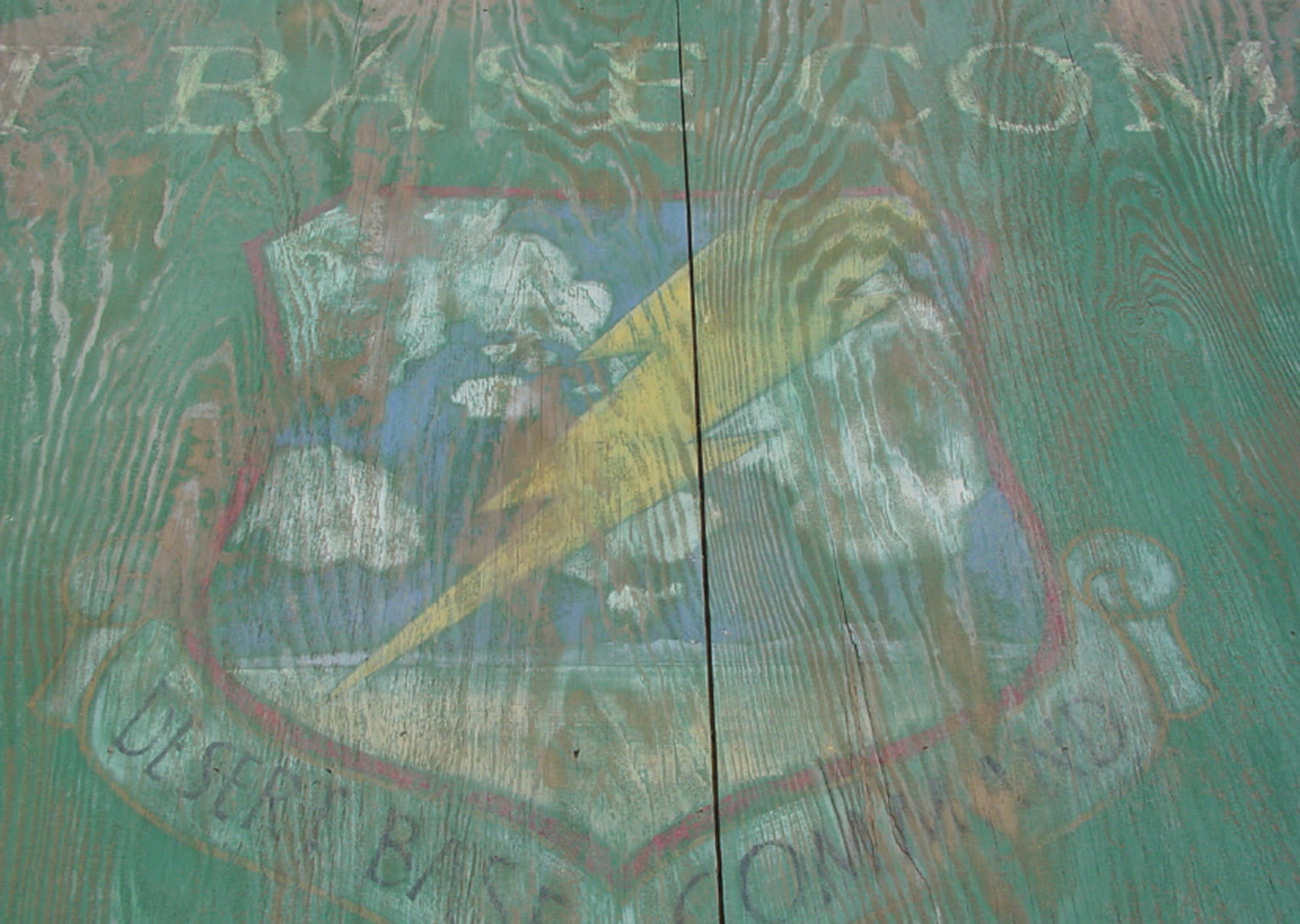 A photograph of detail on a desert base command sign, depicting a lightning bolt hitting a beach.