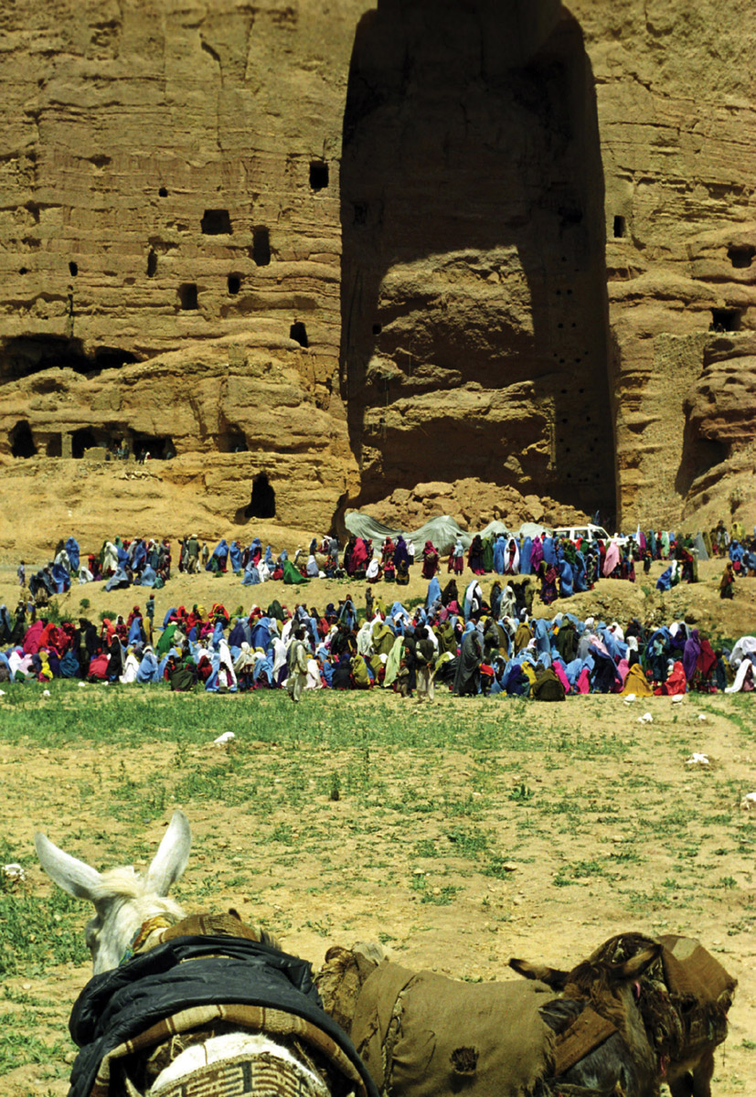 A photograph of families of internally displaced persons camped in front of the cliff that used to house the Buddha statues.