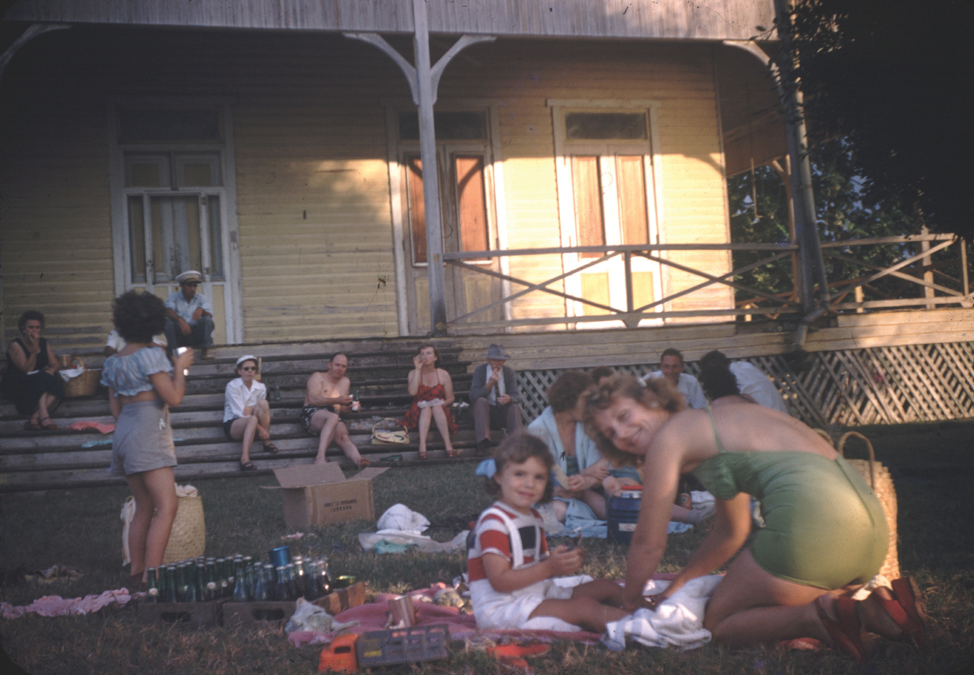 A photograph of families eating and drinking on the grass at a 1951 United Fruit Company picnic at Cayo Saetia.