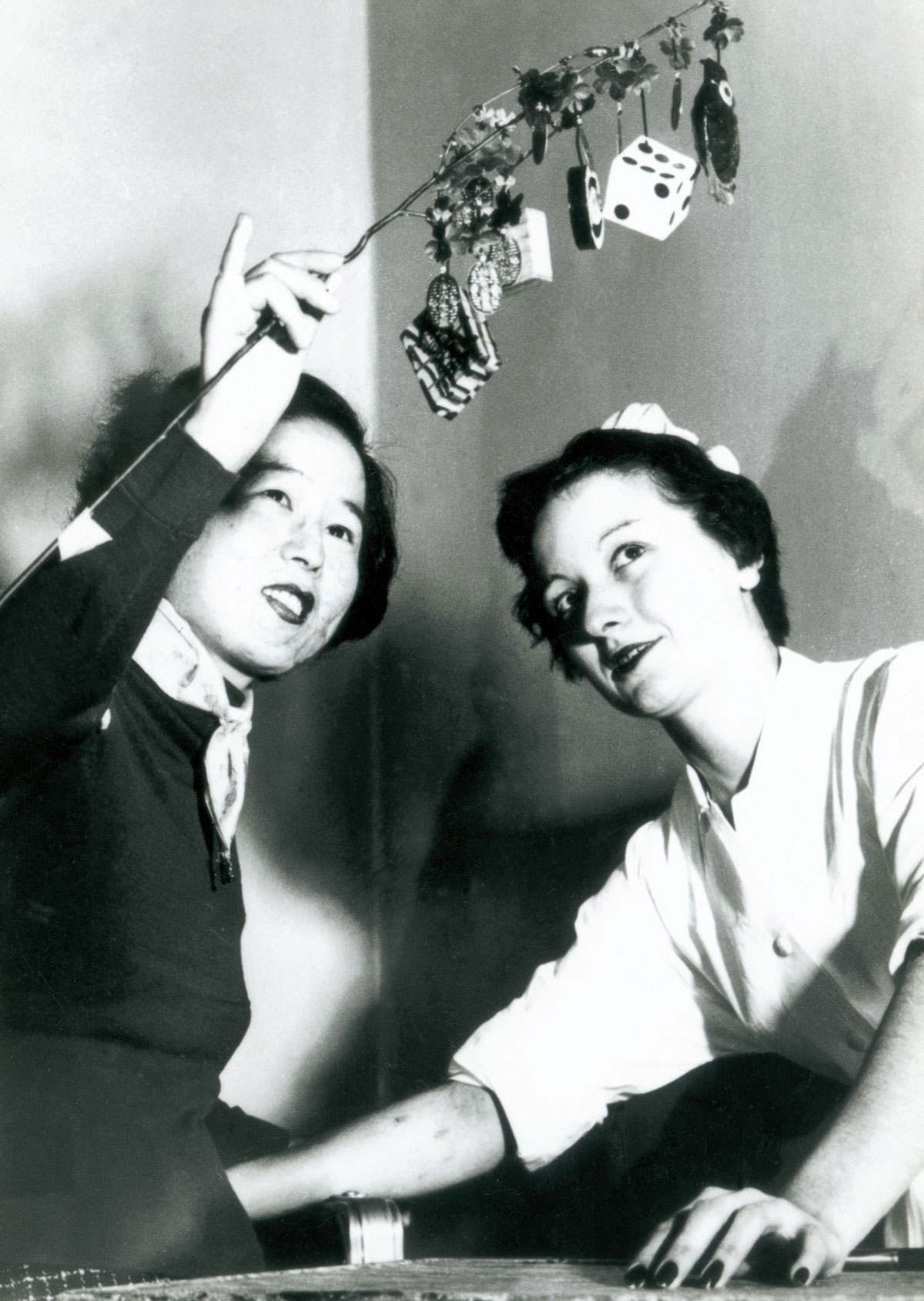 A photograph of a young female survivor of Hiroshima, one of twenty-five so-called Hiroshima Maidens brought to New York for reconstructive surgery, shows her good luck charms to a nurse at Mount Sinai Hospital, 1955.