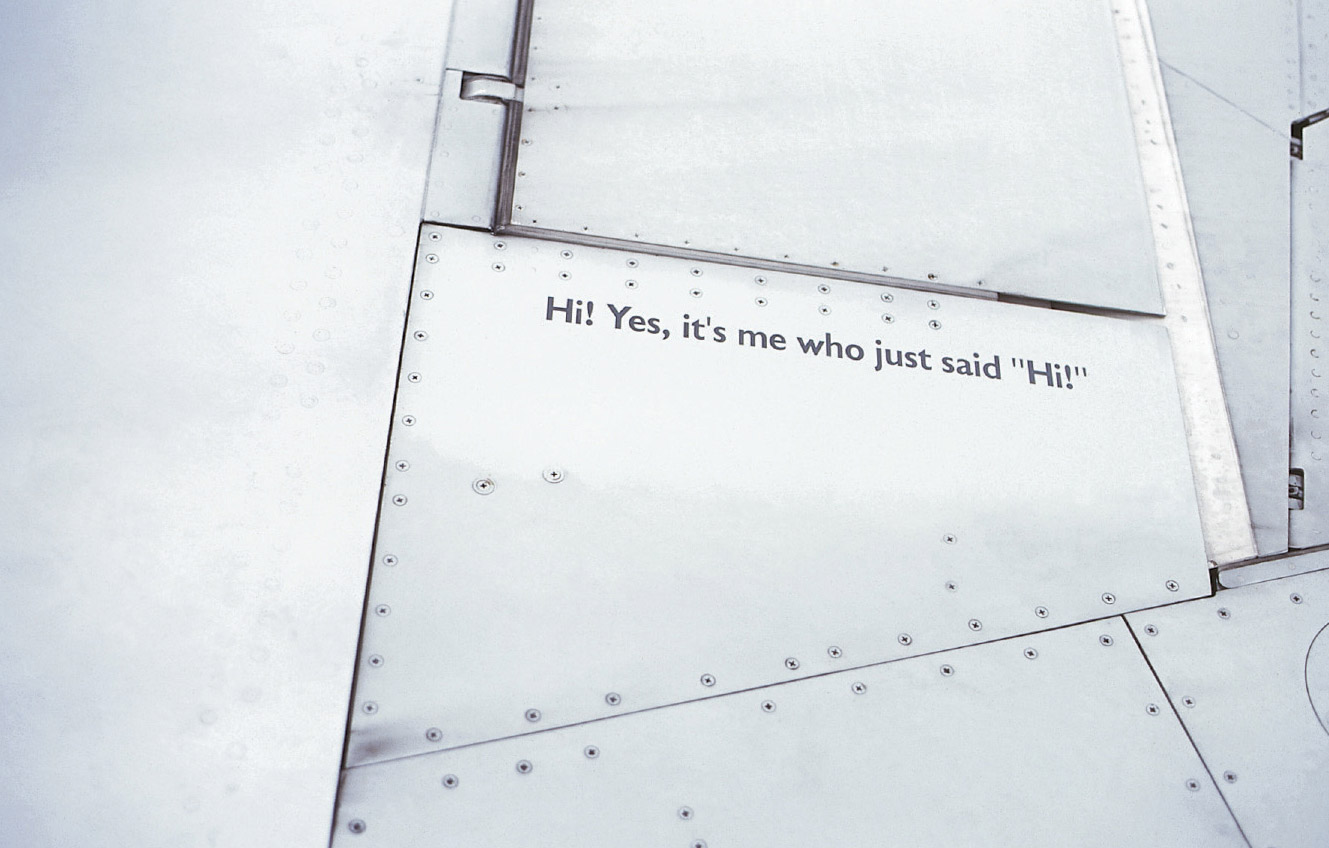 A photograph of text on the wing of an airplane saying hi to the passenger.