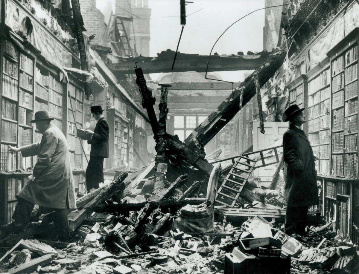 A photograph of people looking through books at the destroyed Holland House Library, London, after a German air raid in October 1940.