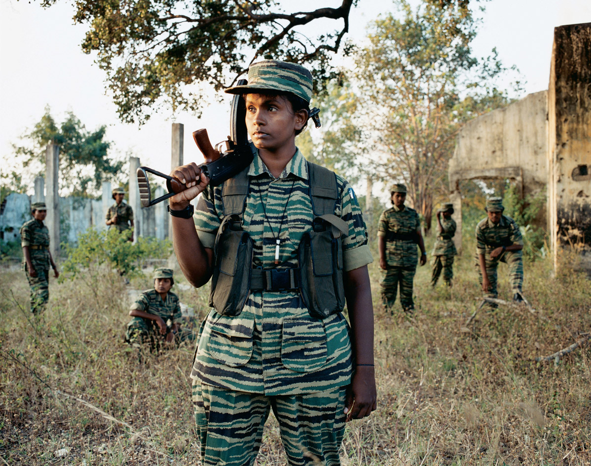 A photograph of a Bird of Freedom member in uniform, holding her gun.