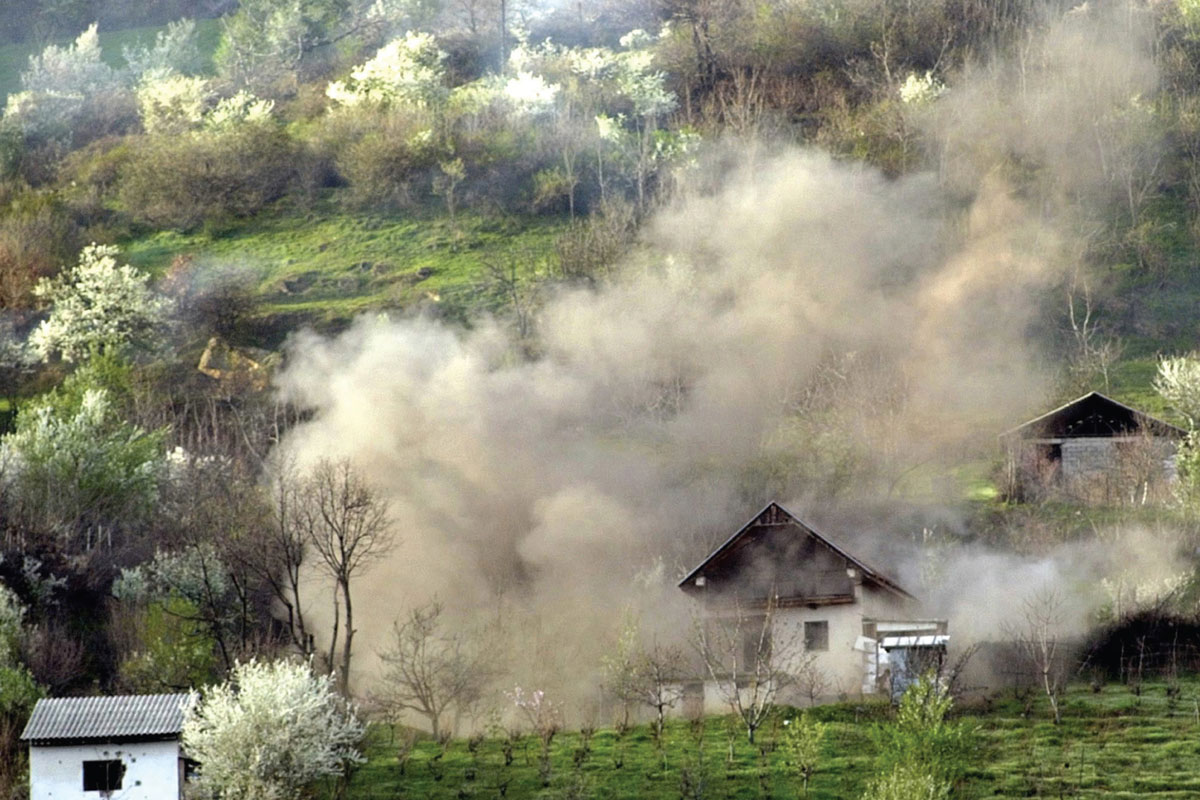 A photograph of a house engulfed in a smoke cloud.