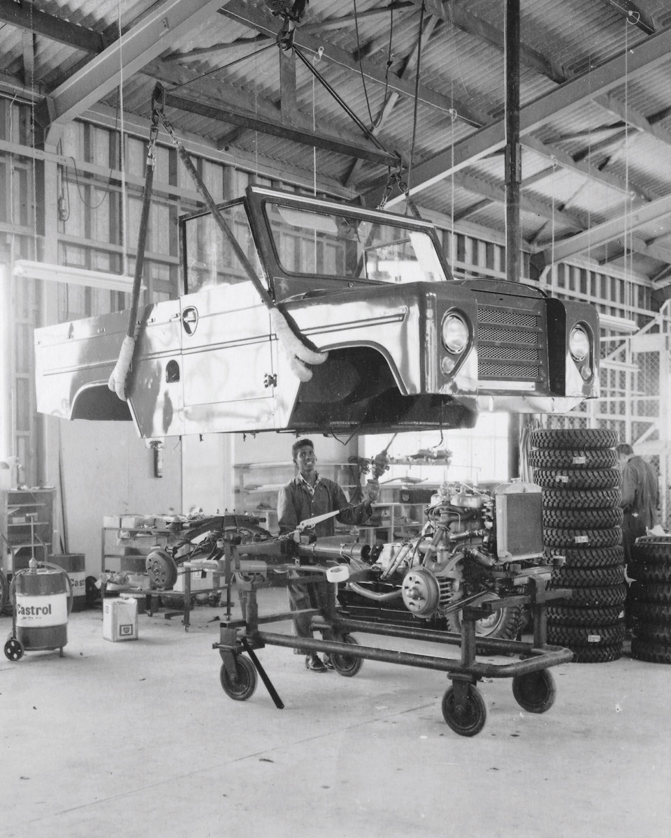 A photograph of a man in a garage assembling a Trekka car.