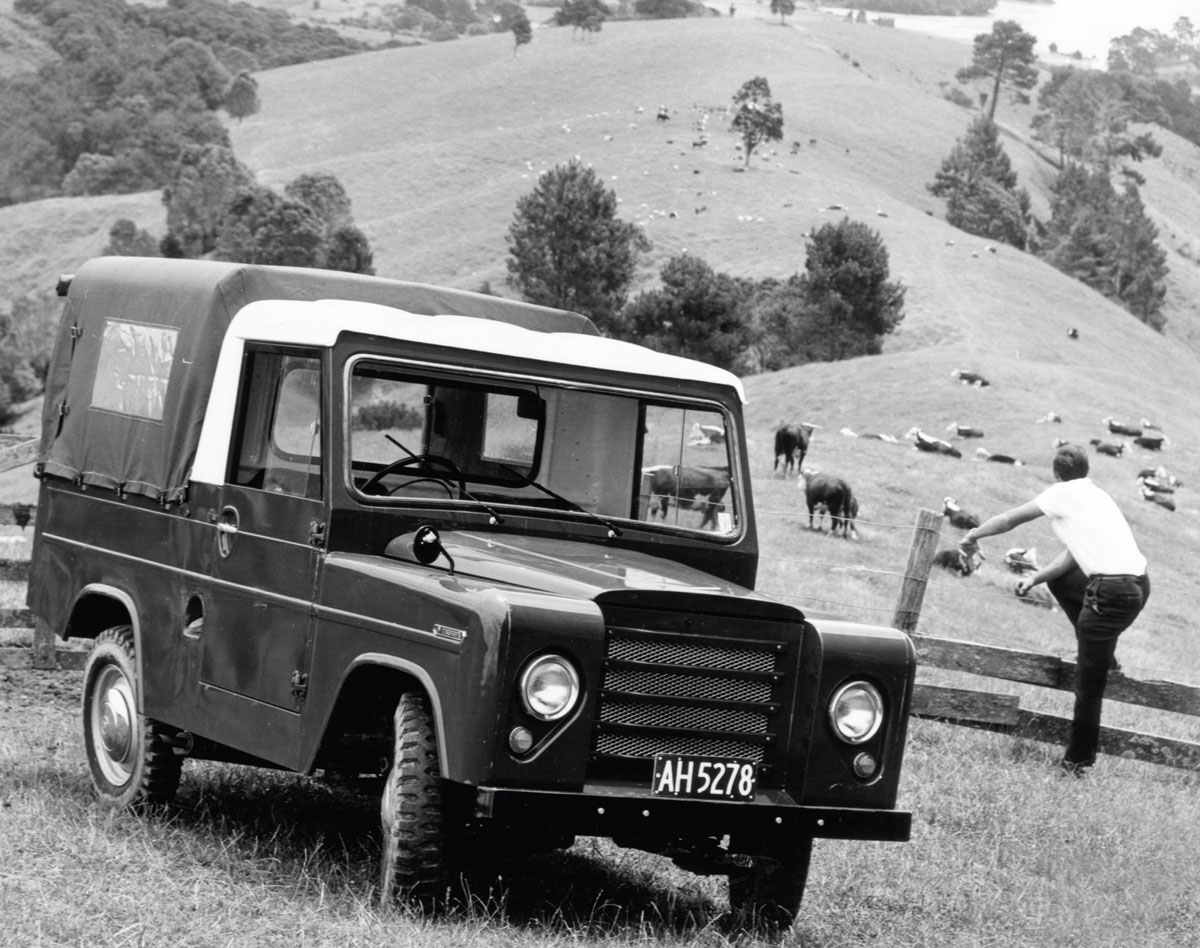 A photograph of a Trekka pulled over on the side of a grassy hill, where cows graze.