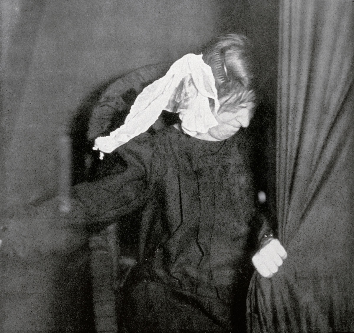 A photograph of Eva C. walking out from behind the curtain during the séance of 22 November 1911.