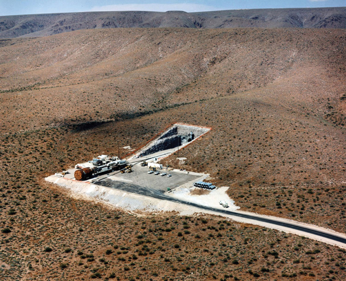 A photograph of the concrete entrance to Yucca Mountain Project, surrounded by desert.
