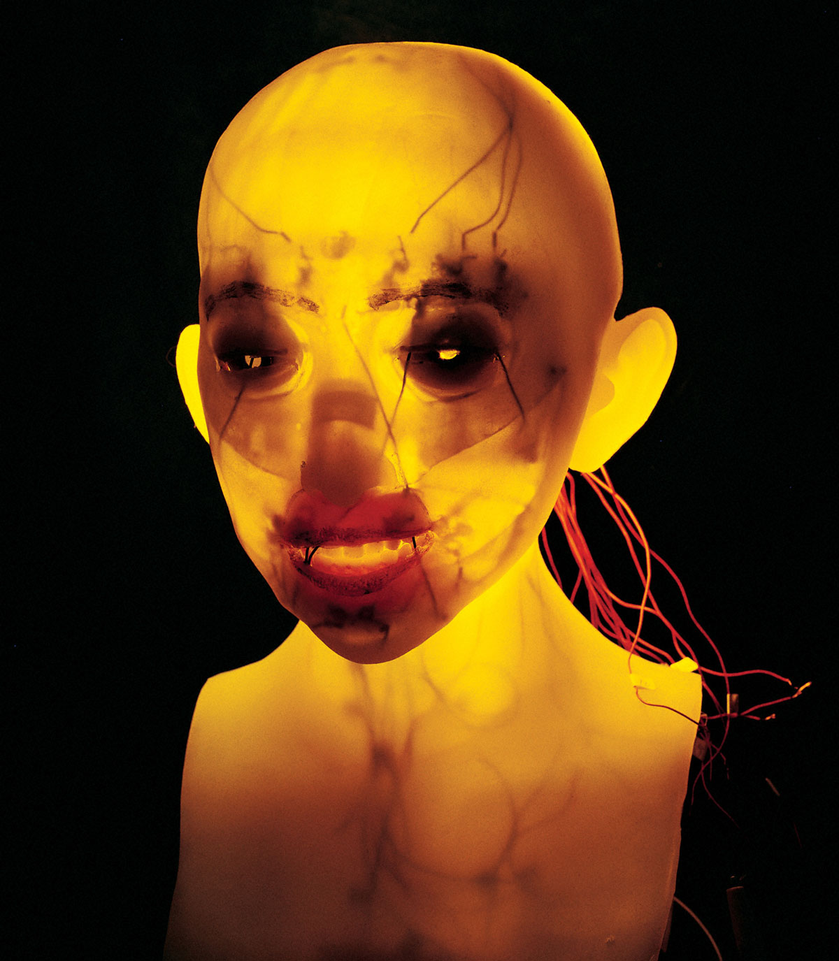 A photograph of an orange glowing bust of a second-generation face robot from Hara-Kobayashi Laboratory.