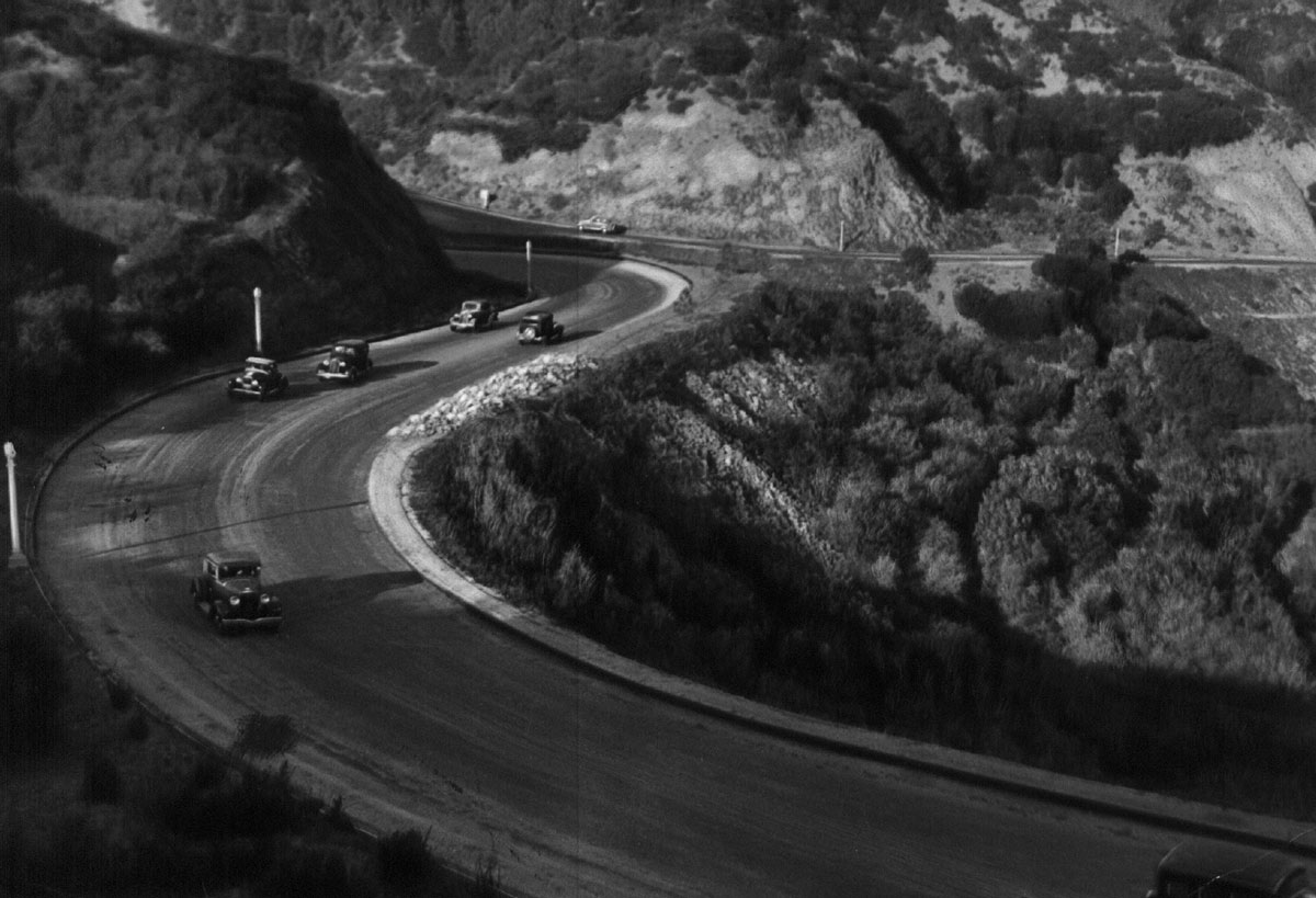 Black-and-white photograph of a winding road surrounded by cliffs.