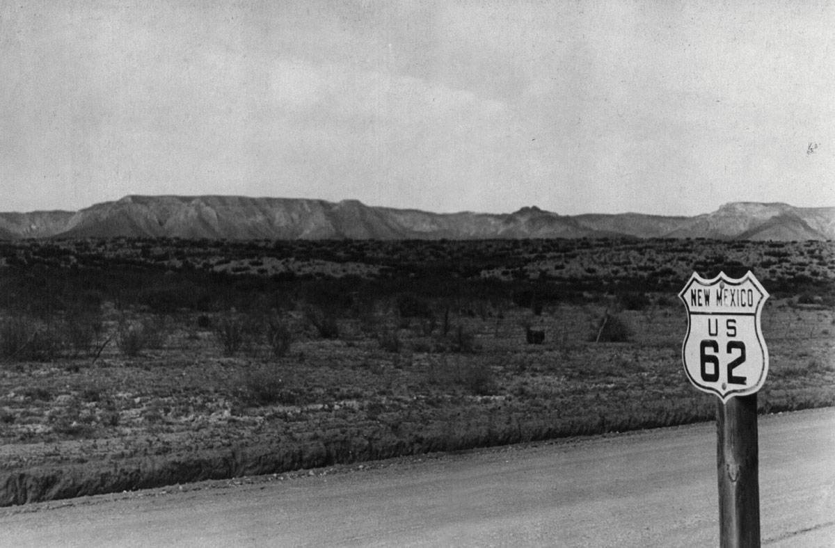 Black-and-white photograph of a US route 62 sign in New Mexico.