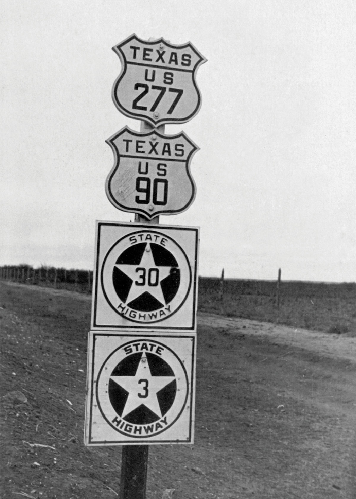 Black-and-white photograph of state highway signs in Texas.