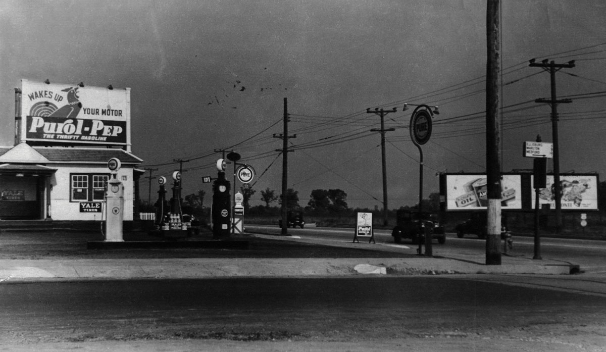 Black-and-white photograph of a gas station on empty corner.