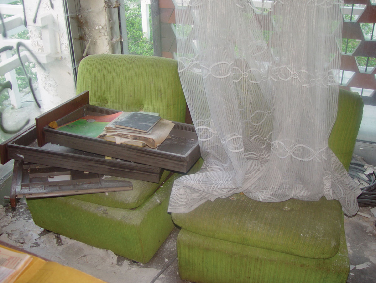 A photograph of broken desk drawers placed on green office chairs.