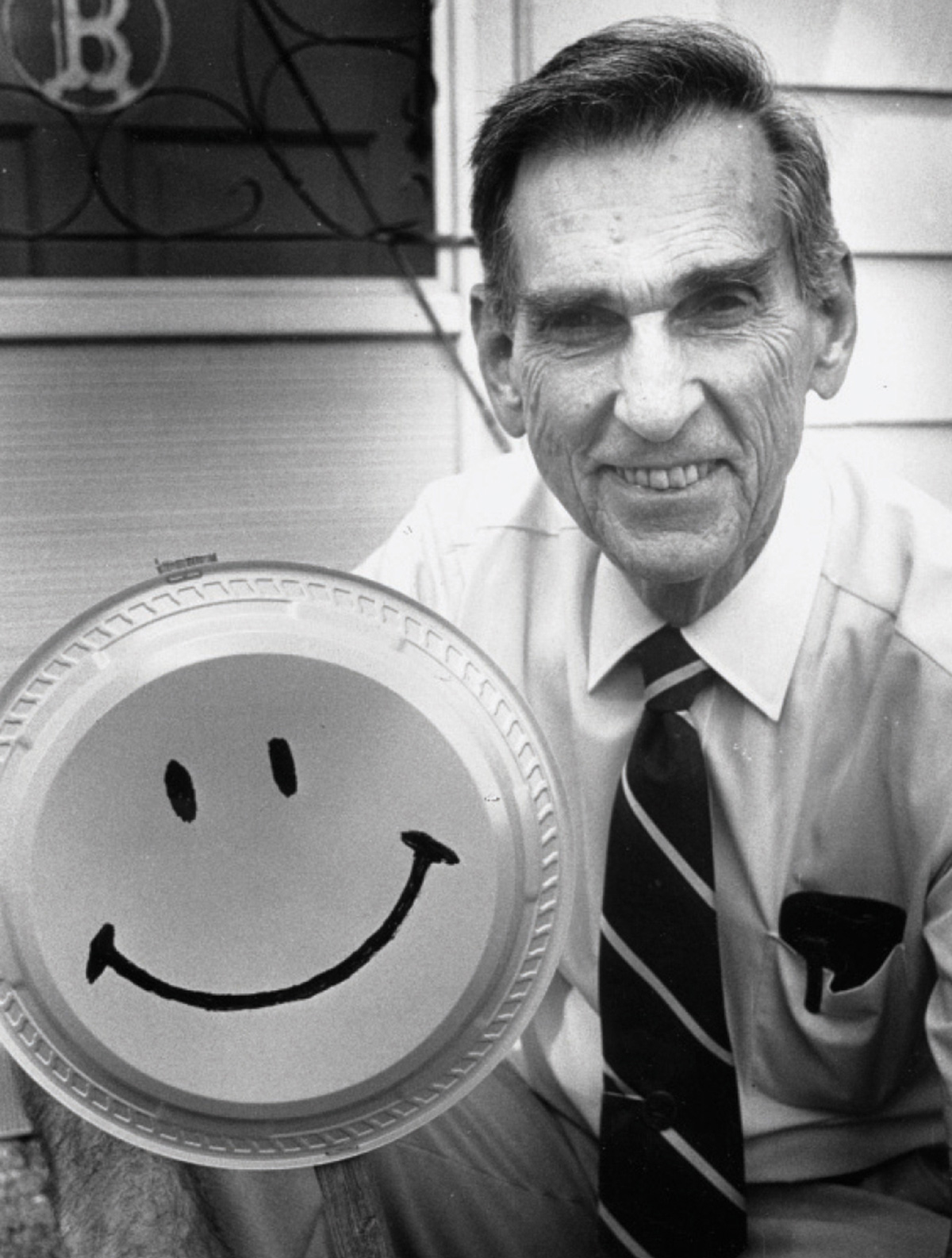 A photograph of Harvey Ball holding up his smiley face design. 