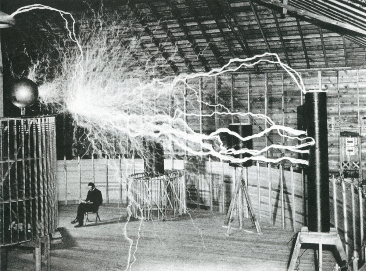Nikola Tesla at his laboratory in Colorado Springs, peacefully reading as millions of volts from his Magnifying Transmitter crackle overhead. In his notes, Tesla identified the photo as a double exposure produced for publicity purposes, ca. 1900.
