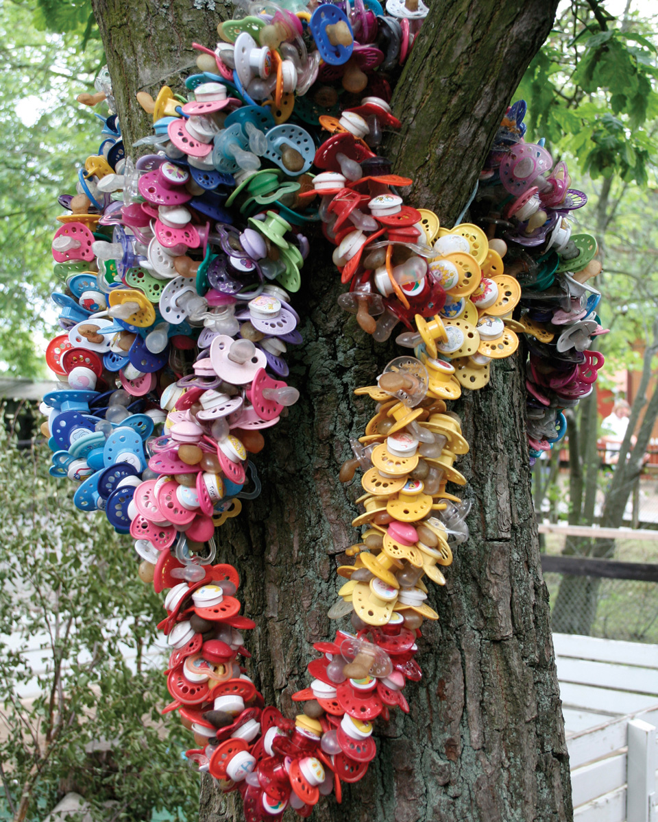 A photograph of a tree in Sweden festooned with pacifiers.