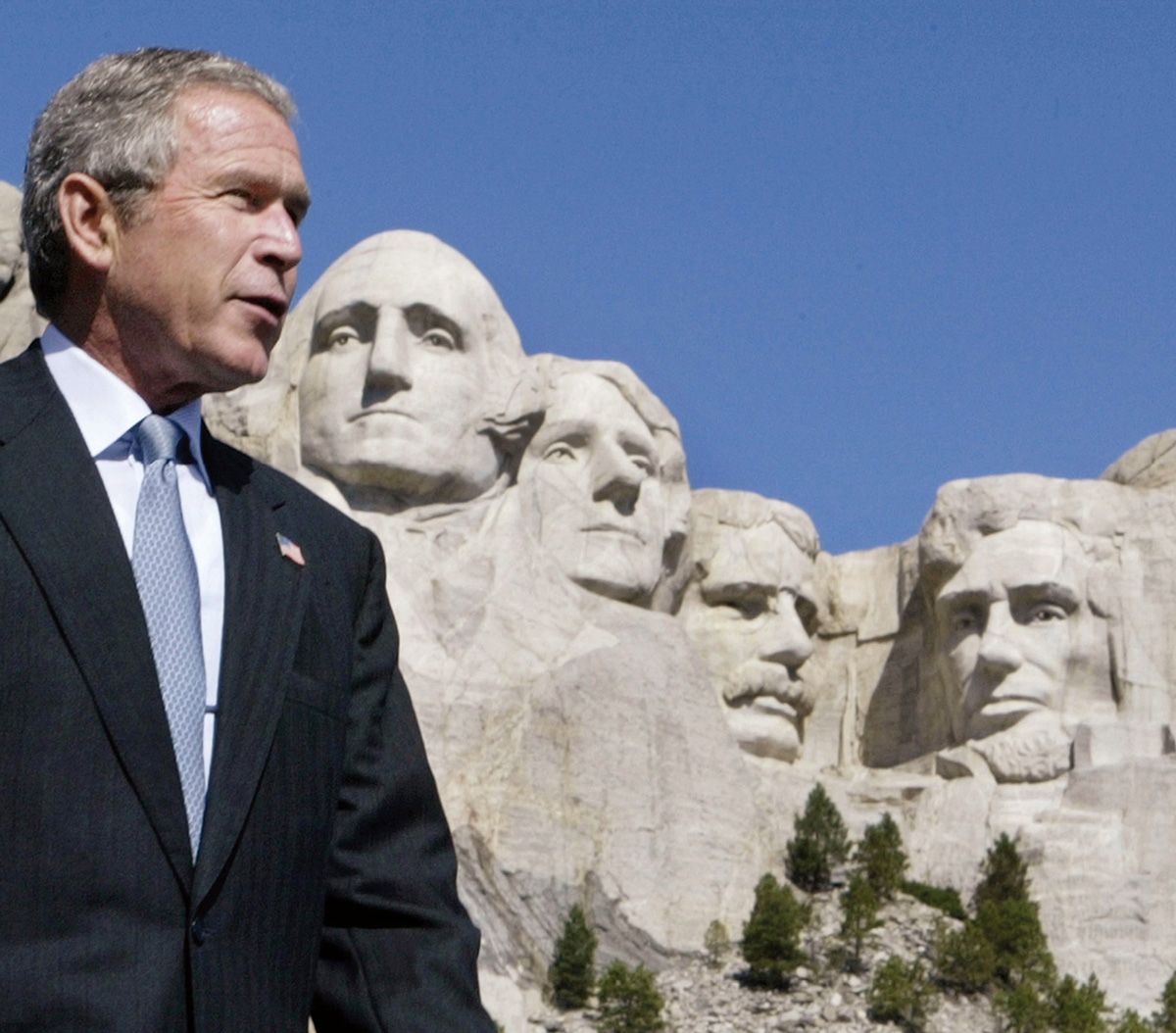A photograph of George W. Bush standing in front of Mount Rushmore, 15 August two thousand two. 