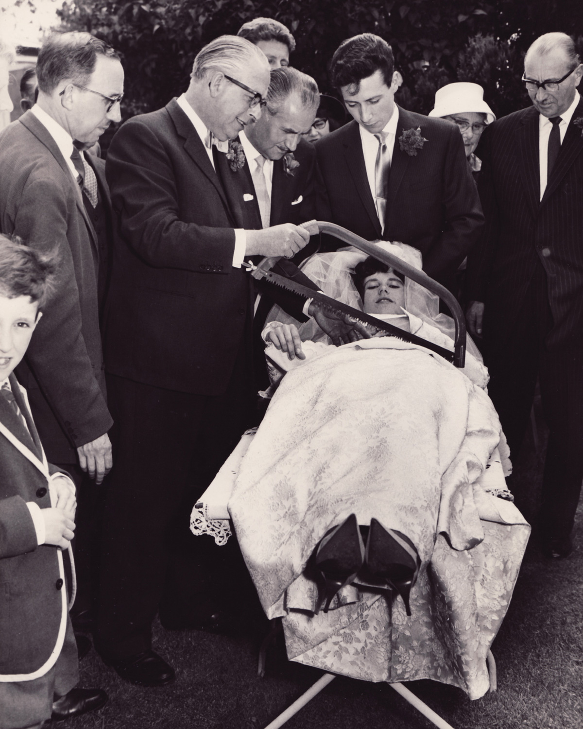 A photograph of Frances White being “sawn in half” by here father at her wedding. White had often helped her father, Francis, in his stage illusions, including this very trick. Original caption for the photograph reads: “Mr. Francis White ‘saws’ his daughter in half—for the last time—after her marriage this morning. … The groom looks on…”