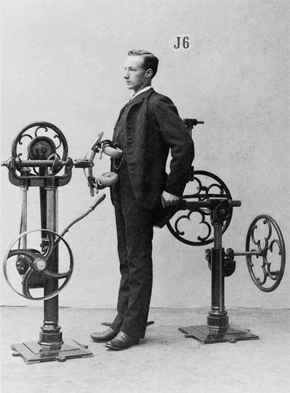 A nineteen-eighties photograph of a man in a suit standing in front of a Zander exercise machine, which is rolling his abdomen.