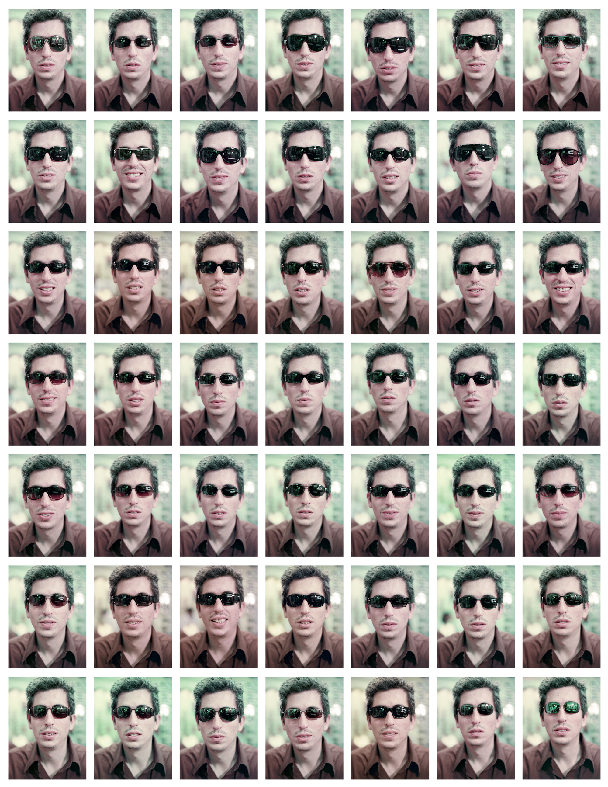 Forty nine small photographs, arranged in a seven by seven grid, of artist San Keller wearing different sunglasses.