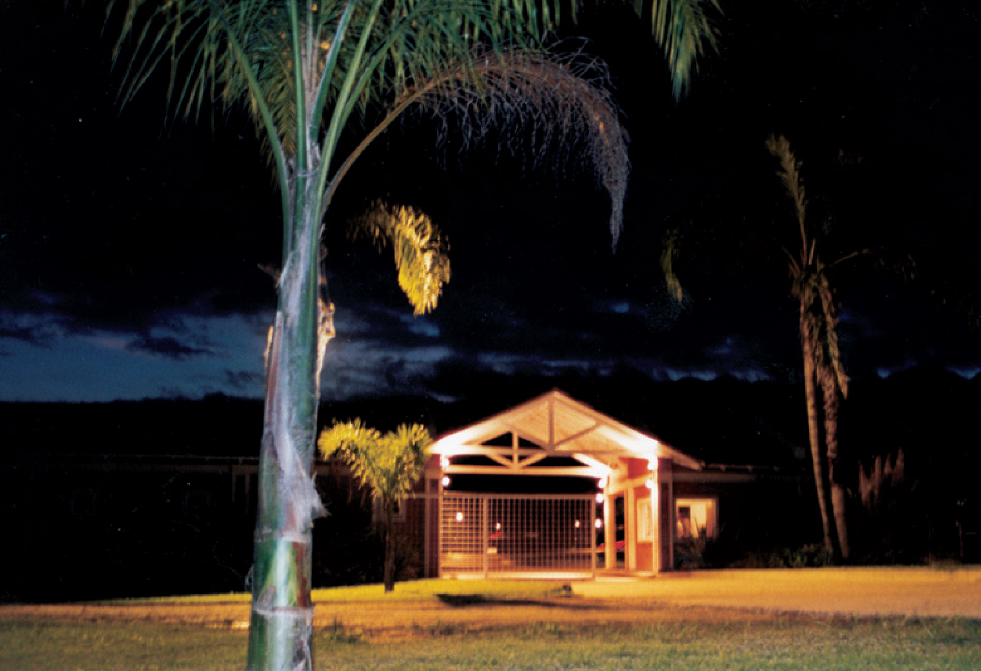 A photograph of the entrance of a “country” at night with lights on inside the structure.