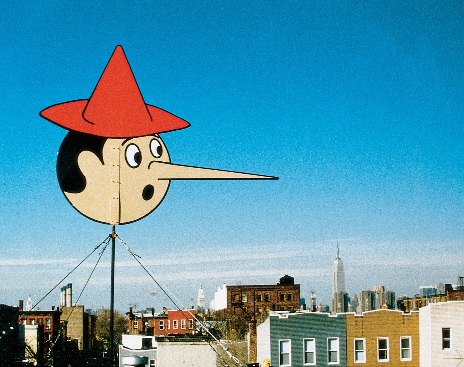 A postcard project by artist Michael Ballou featuring a photograph of his Pinocchio-themed weather vane.