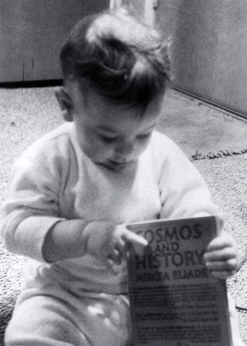 A 1959 photograph of Dorion Sagan holding Mircea Eliade’s book “Cosmos and History.” 