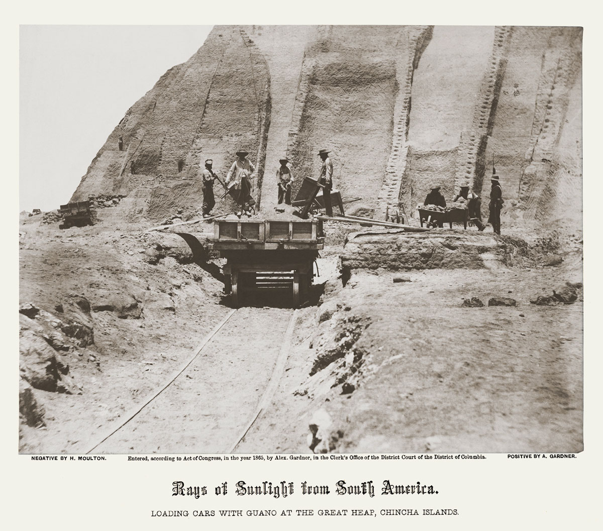 An eighteen sixty-five photograph by Alexander Gardner titled “Loading Cars with Guano at the Great Heap, Chincha Islands.”