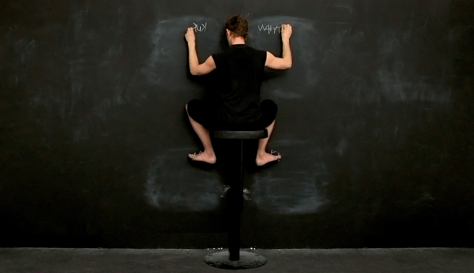 A photograph of a woman writing on a chalkboard using all four limbs. 