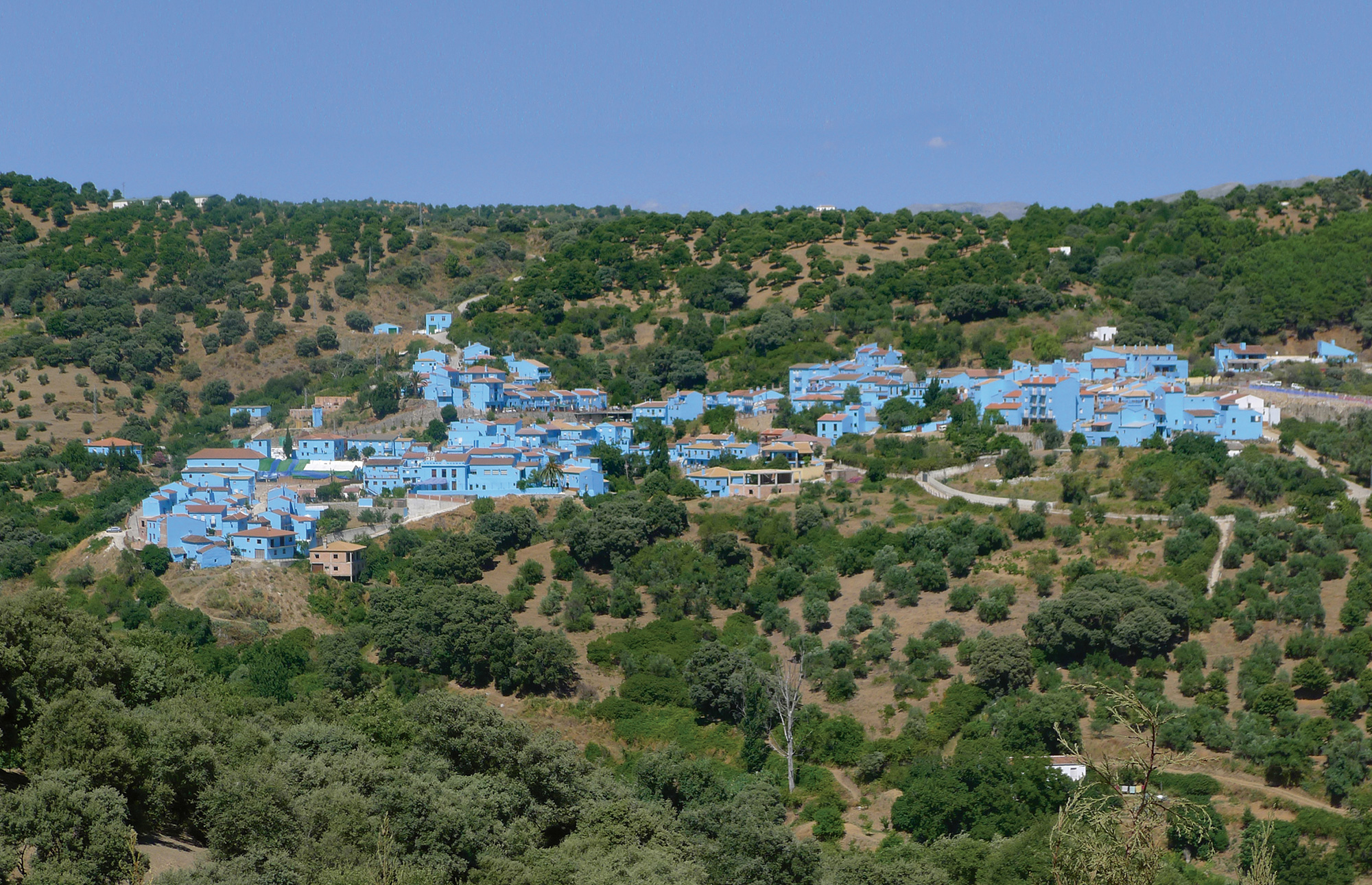 A photograph of the southern Spanish village of Júzcar, post-Smurfification. All the buildings on this hillside are painted Smurf blue.