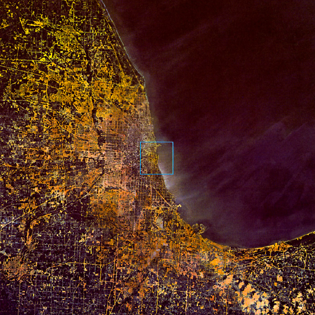 A photograph of a coastline at night show from above, from the nineteen eighty-two book version of “Powers of Ten,” by Philip and Phylis Morrison and the Office of Charles and Ray Eames.
