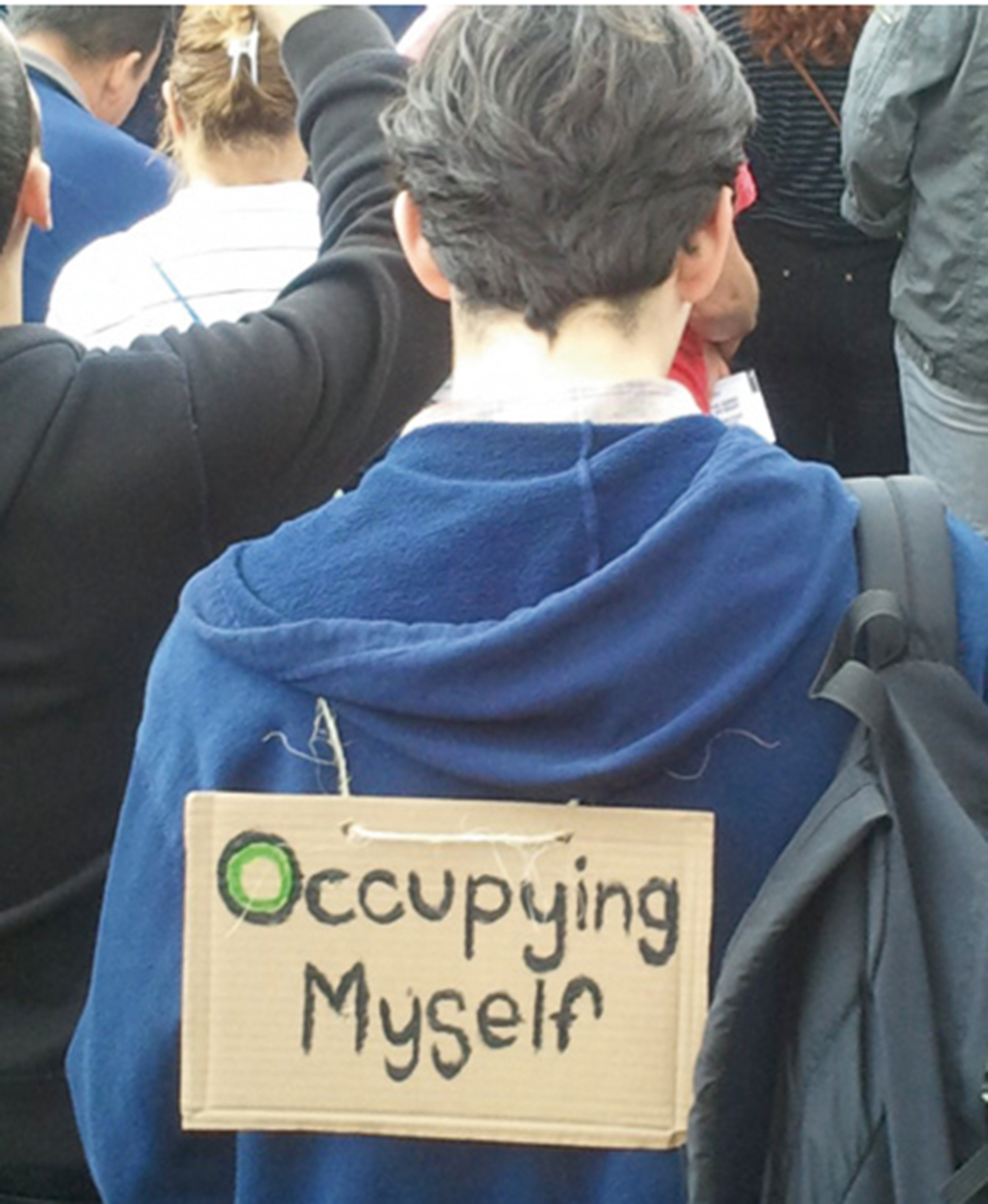 A twenty eleven photograph of a person wearing a protest sign that reads “Occupying myself.”
