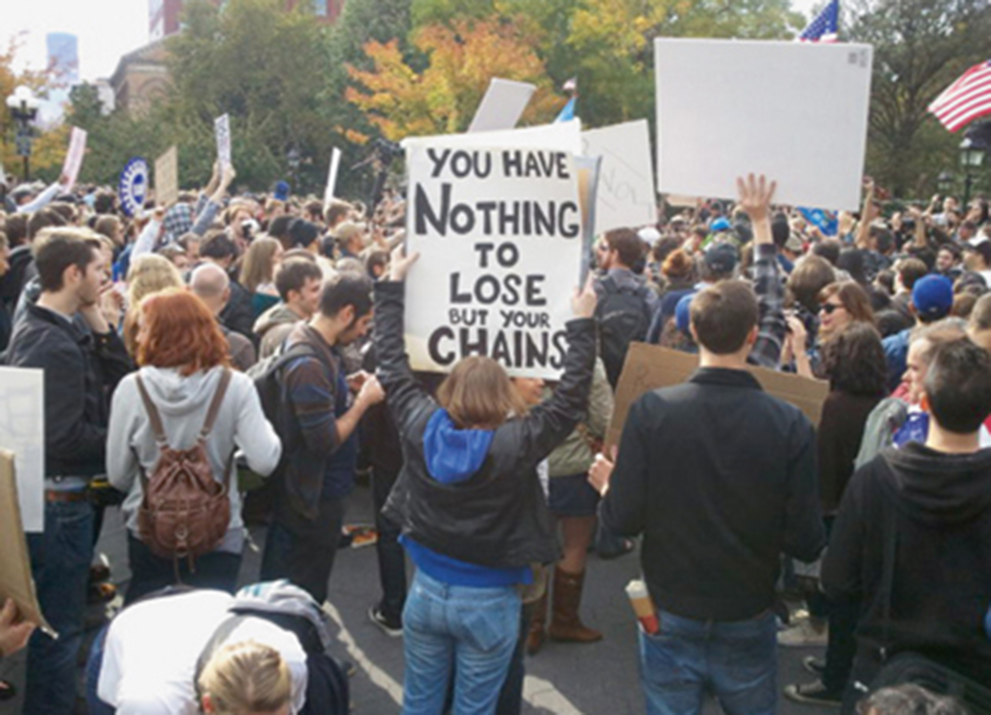A twenty eleven photograph of a person holding a protest sign that reads “You have nothing to lose but your chains.”