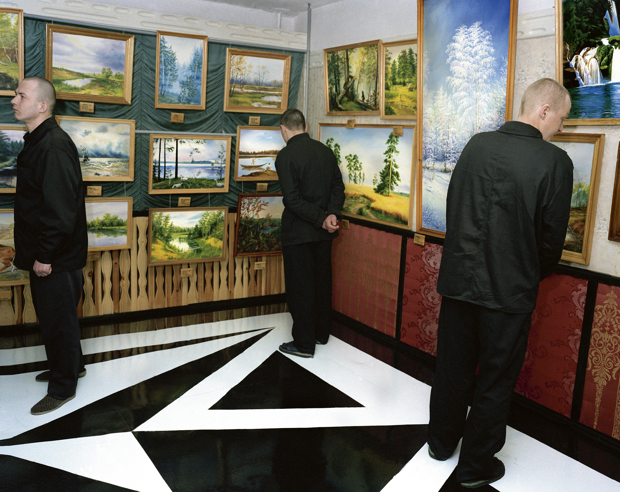 A two thousand photograph of Camp 27 in Krasnoyarsk, Siberia. It shows prisoners looking at paintings made in the camp. During a two-week vacation spent in a camp building, prisoners are allowed to paint, have saunas, and live in more private rooms.