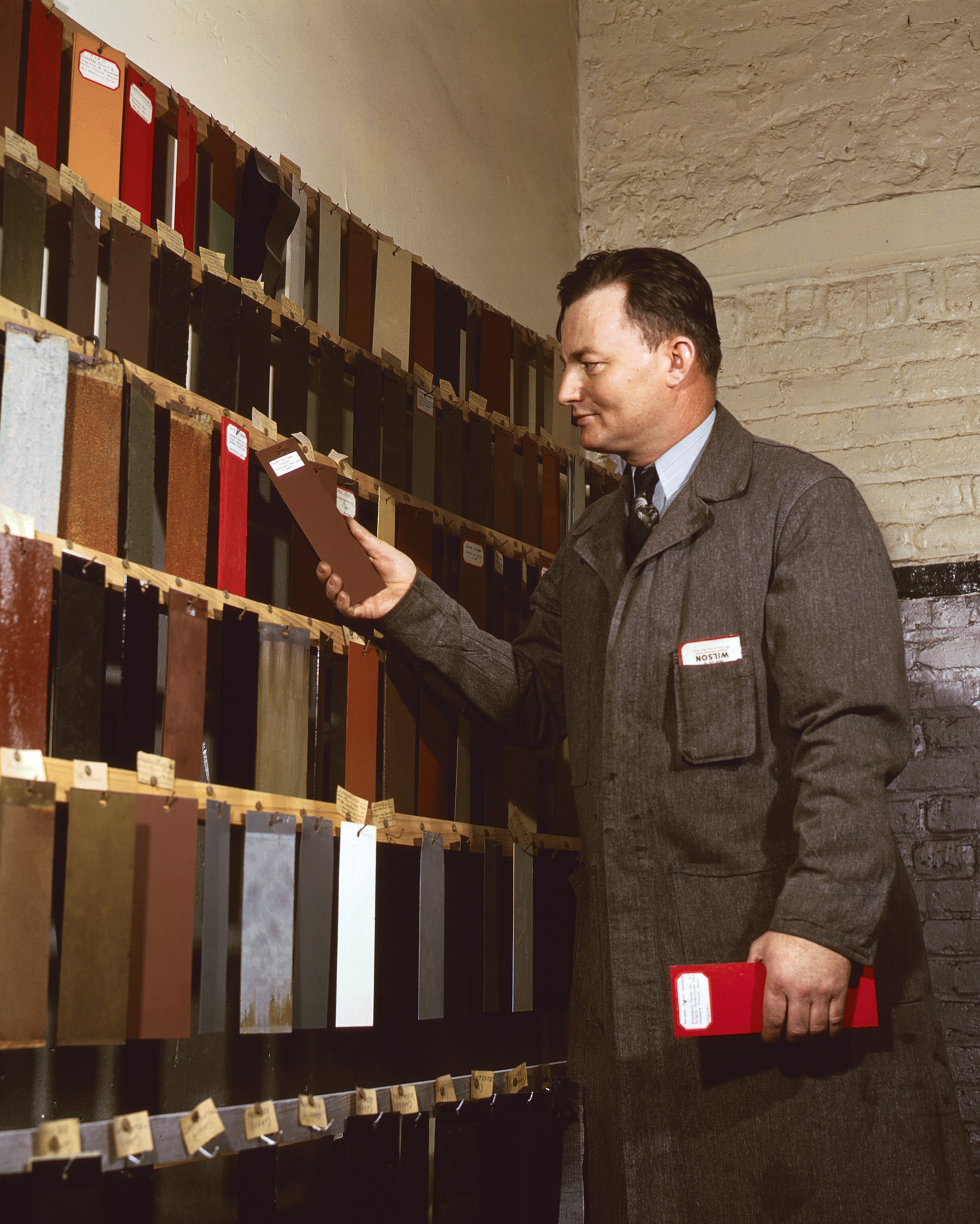 A photograph of a man inspecting linoleum samples. 