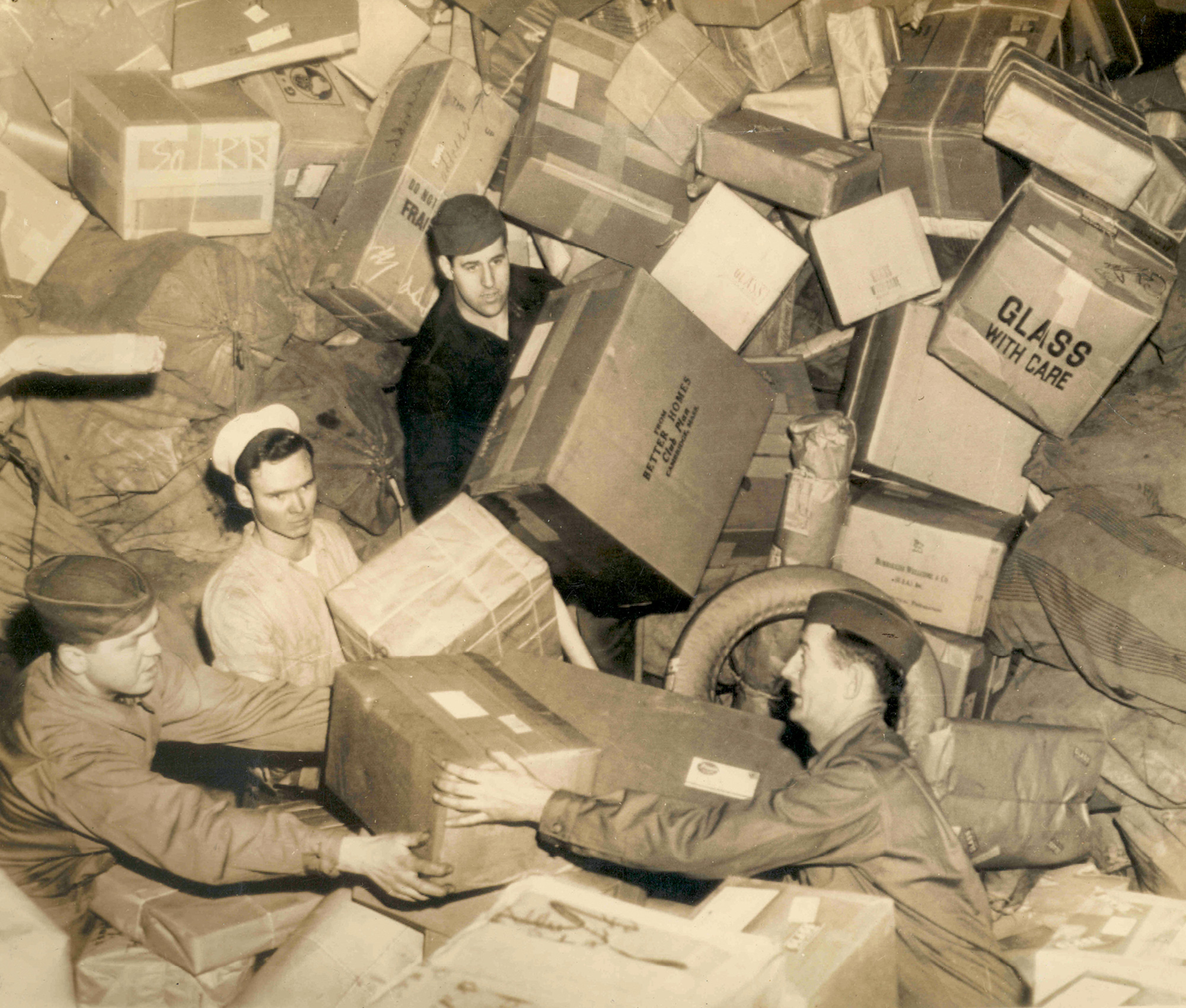 American military personnel amid a mountain of holiday packages, ca. 1944.