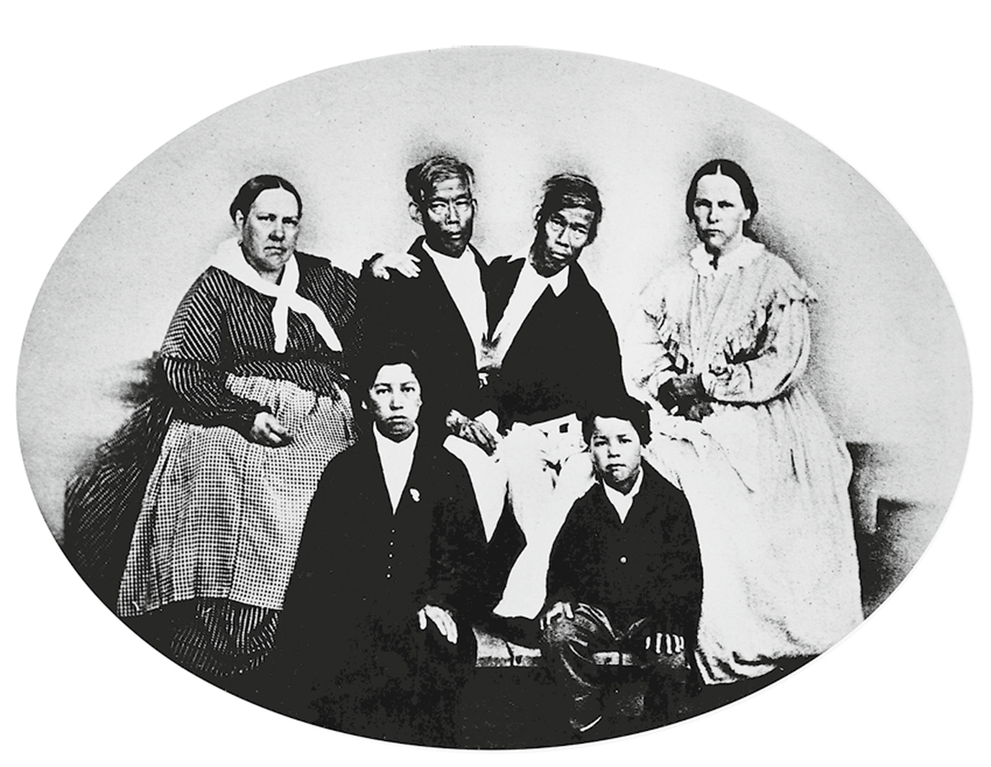 A circa eighteen sixty-five photograph of the conjoined twins Chang and Eng Bunker, surrounded by their wives and two of their sons.