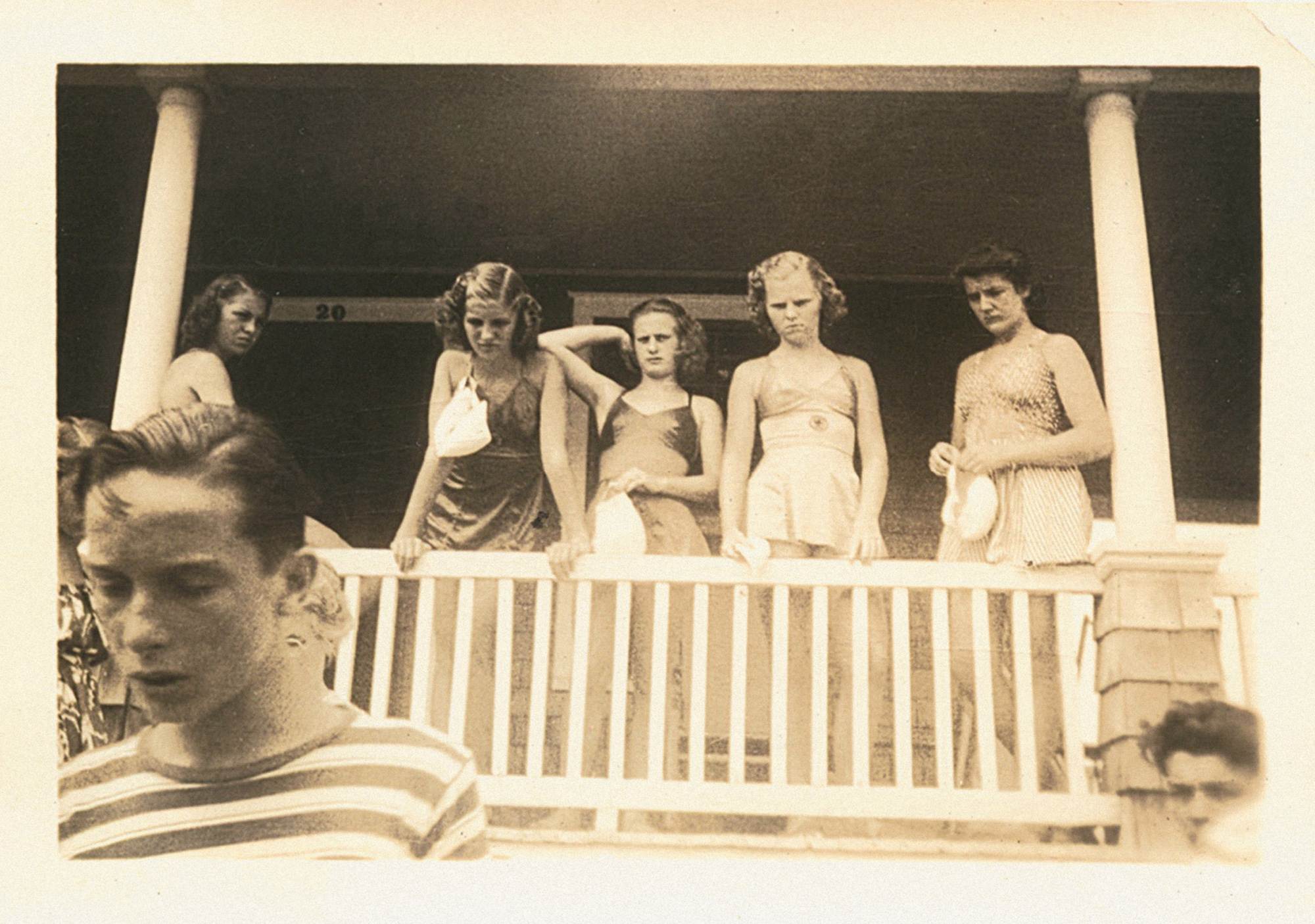 A photograph of girls in summer dresses on a porch.